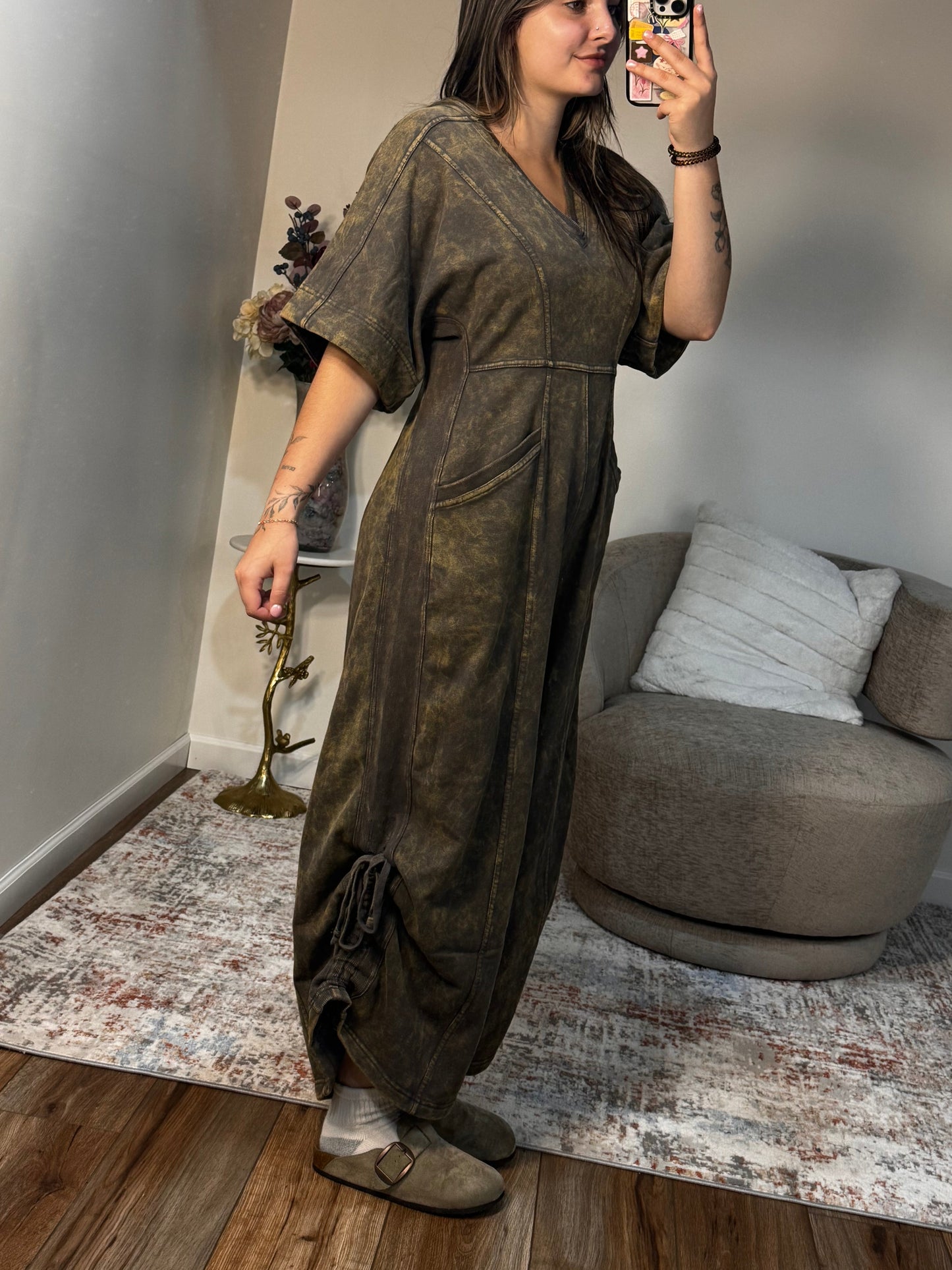 Person taking a mirror selfie in a room with a sofa and wooden floor.