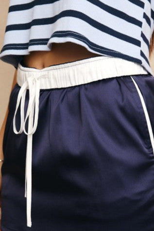 Navy blue skirt with white drawstring and trim worn by a person on a beige background
