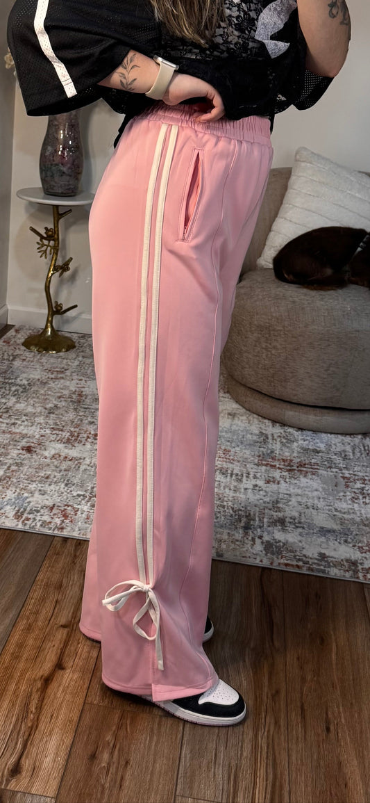 Person wearing a black and white top and pink pants with white stripes indoors.