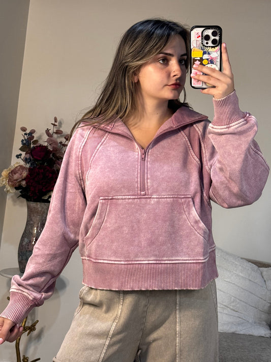 Person wearing a pink hoodie taking a mirror selfie in a room.