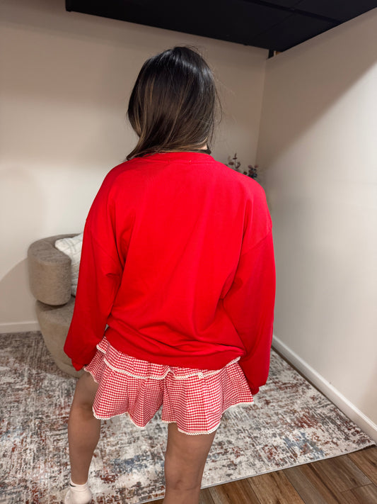 Person wearing a red dress with a checkered skirt in a room.