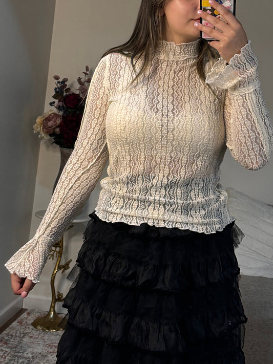 Person wearing a beige lace dress standing in front of a mirror.