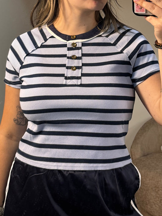 Person wearing a black and white striped shirt with tattoos on arms and neck.