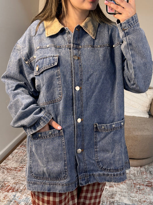 Person wearing a denim jacket in a room with a couch and rug.