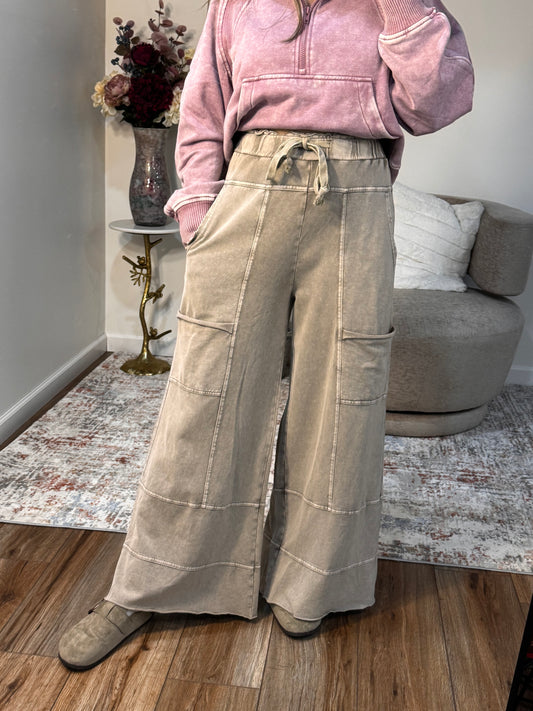 Beige pants on a hanger in front of a sofa with a pink jacket draped over it.