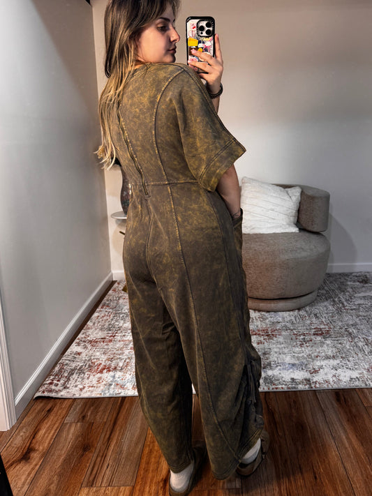 Person taking a mirror selfie in a room with a couch and wooden floor.