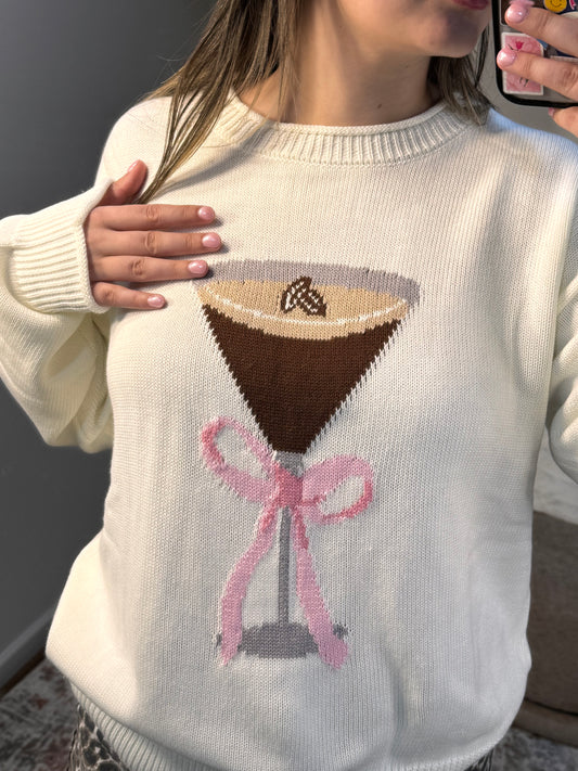 Close-up of a sweater with a design of a drinkand a pink bow.