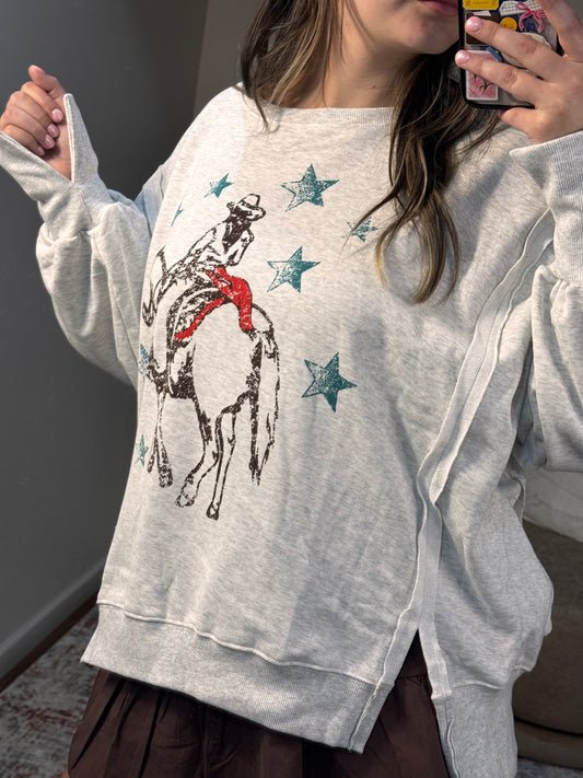 Person wearing a light gray sweatshirt with a graphic design of a horse and stars.
