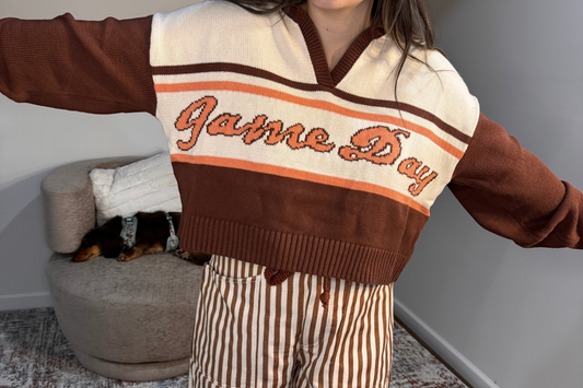 Person wearing a 'Game Day' sweater with a dog in the background