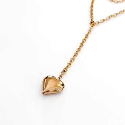 Gold necklace with a heart-shaped pendant on a white background.