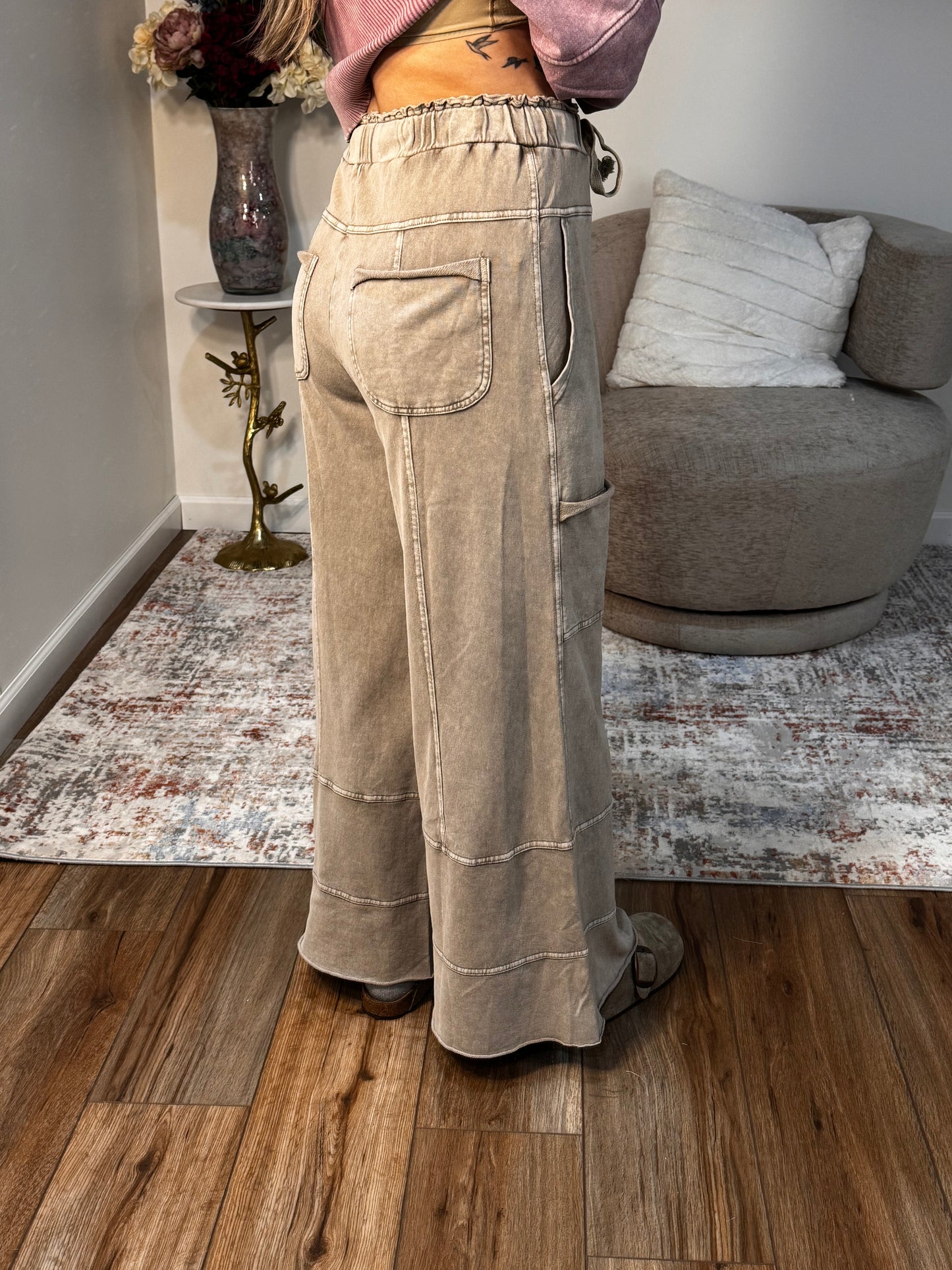 Beige pants displayed on a mannequin in a room with a sofa and wooden floor.