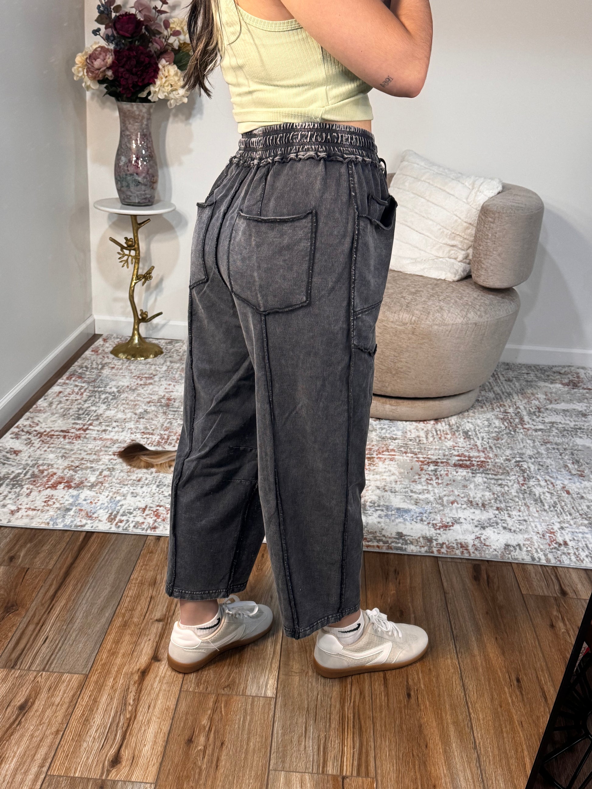 Person wearing black pants standing in a room with a couch and table.