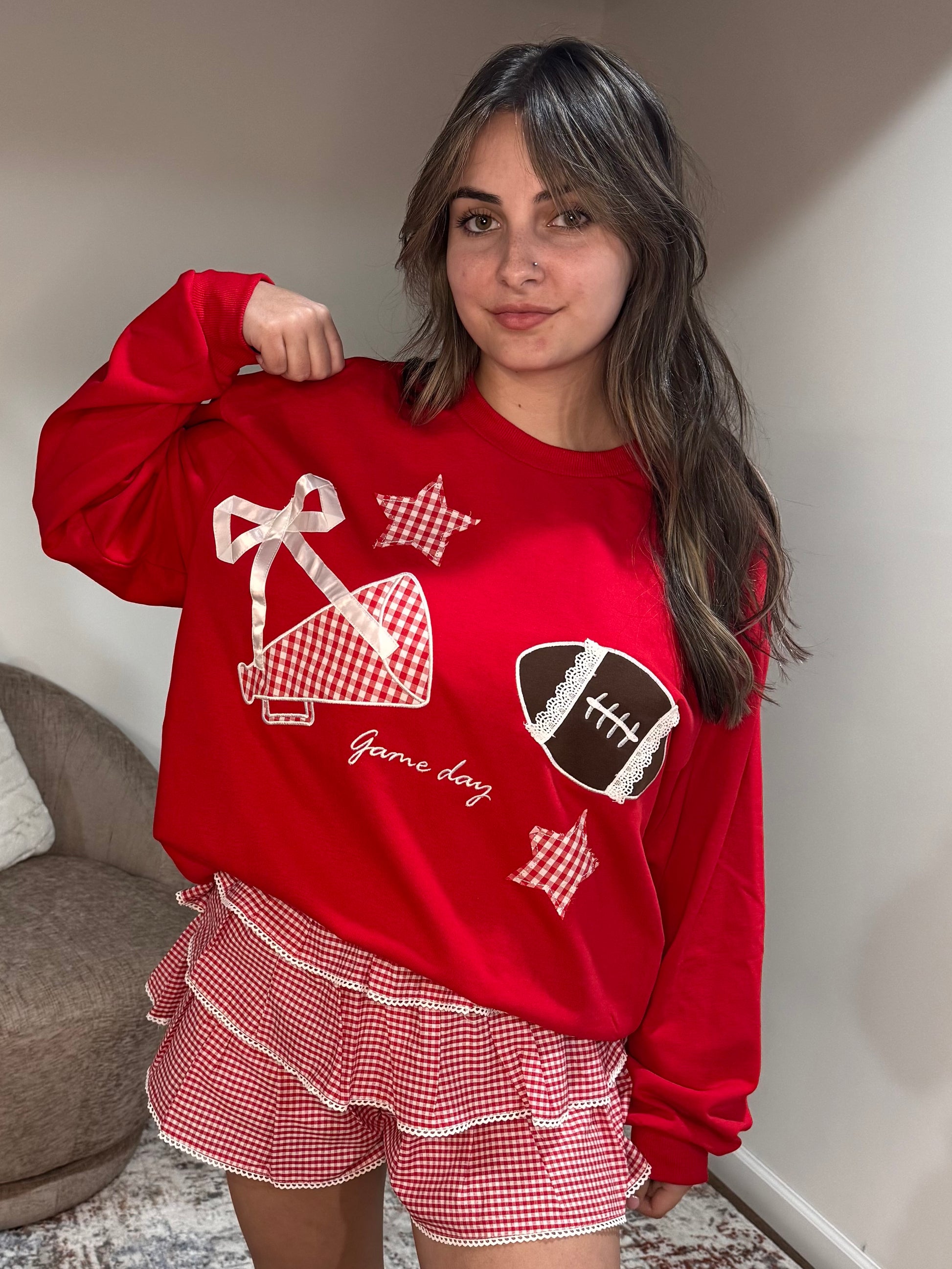 Woman wearing a red sweatshirt with sports-themed designs and matching shorts.