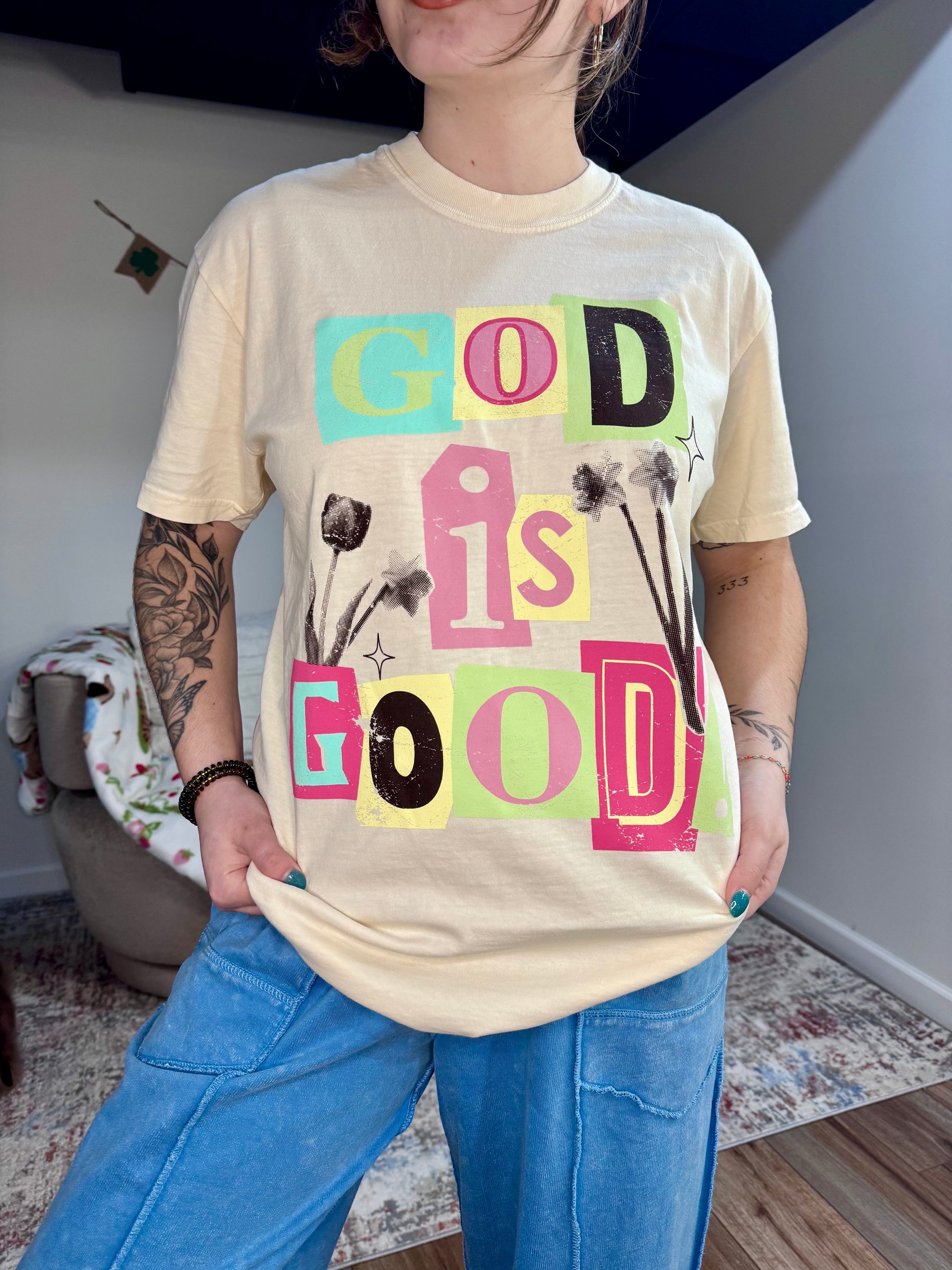 Person wearing a t-shirt with 'GOD IS GOOD' text in colorful letters.