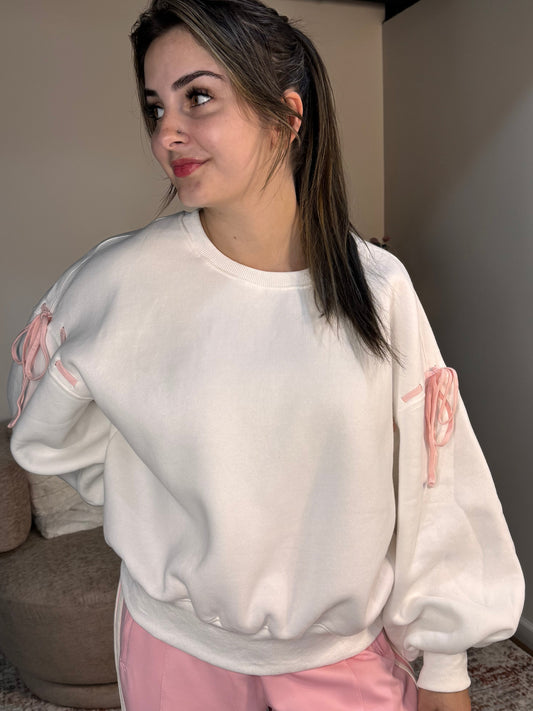 Person wearing a white sweatshirt with pink designs and pink pants in a room.