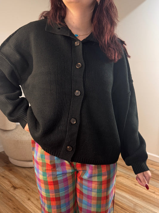 Black oversized cardigan with high neck, button-up front, and ribbed detail worn by a person.
