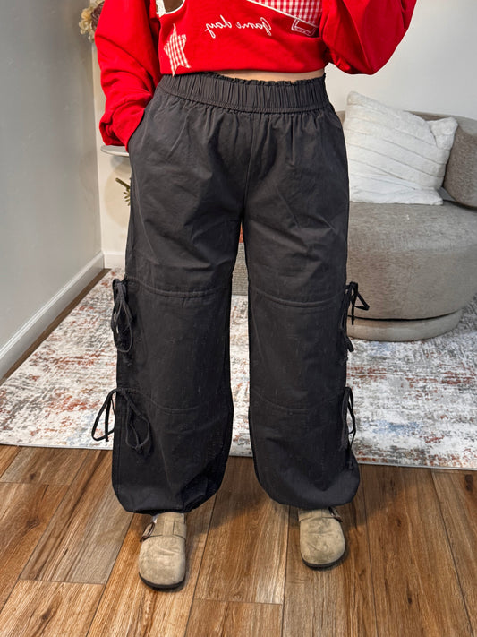 Person wearing a red hoodie and black snow pants standing on a wooden floor.