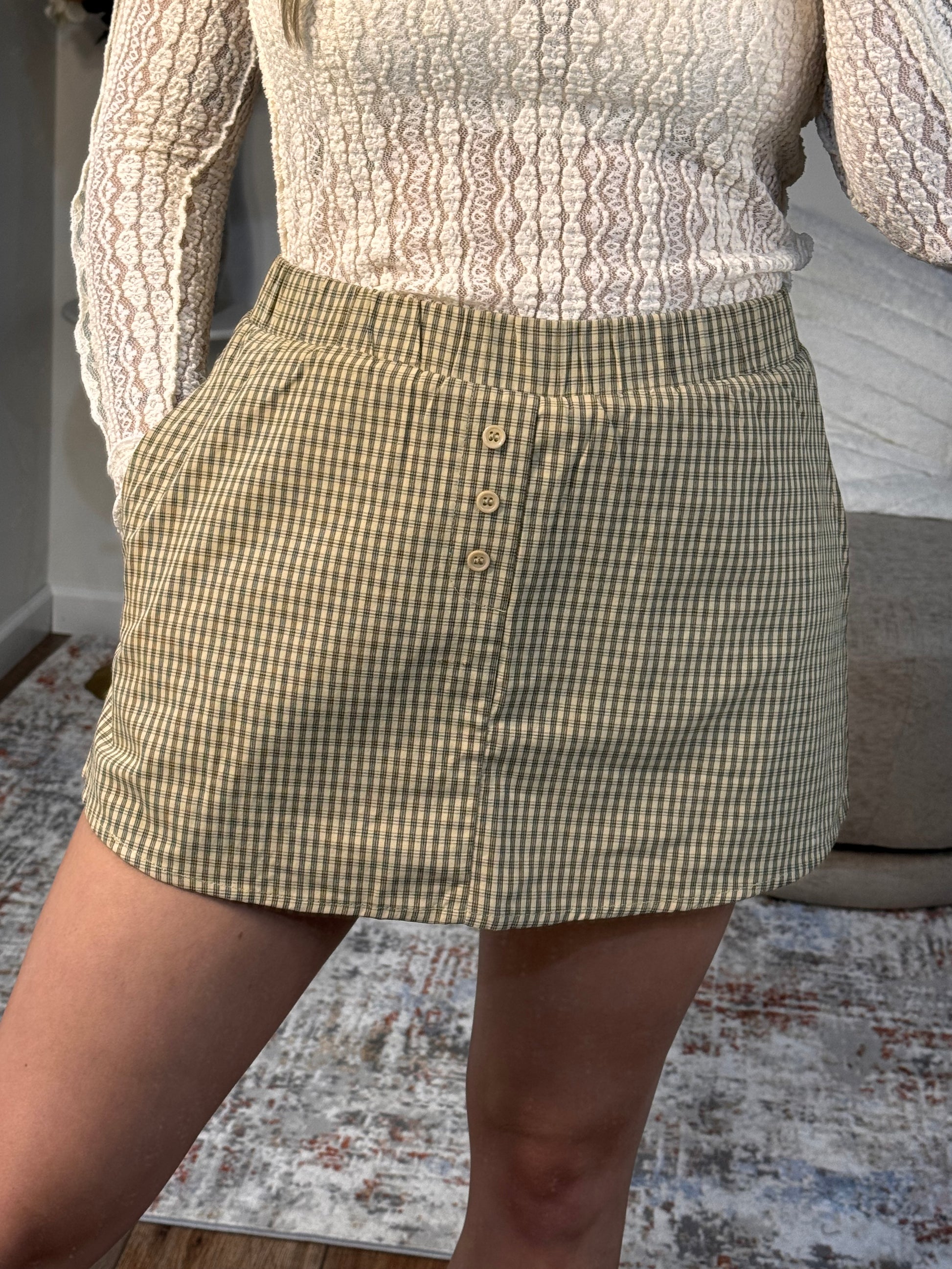 Green checkered shorts being held up against a neutral background