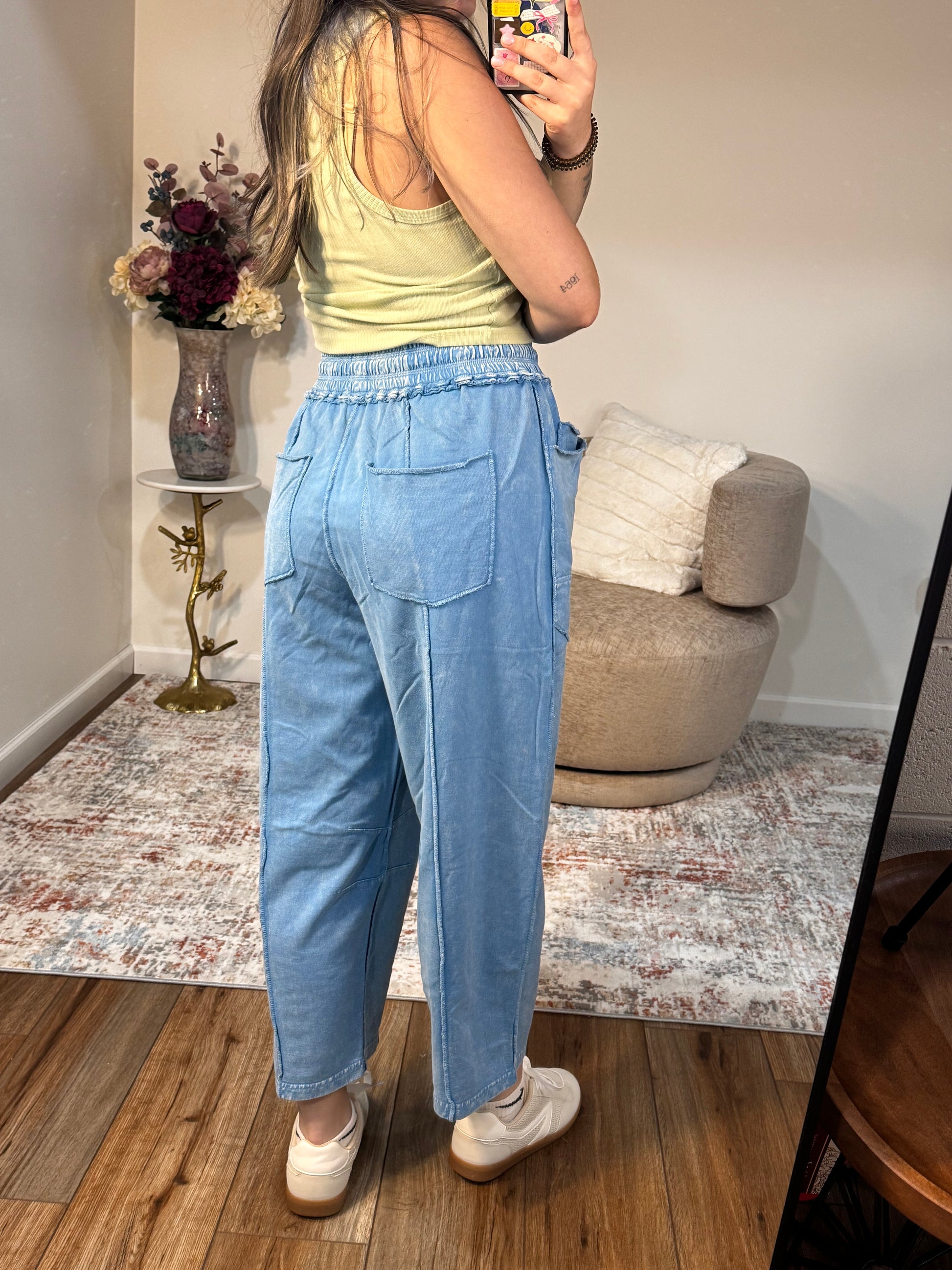 Person wearing blue pants standing in a room with a couch and decorative items.