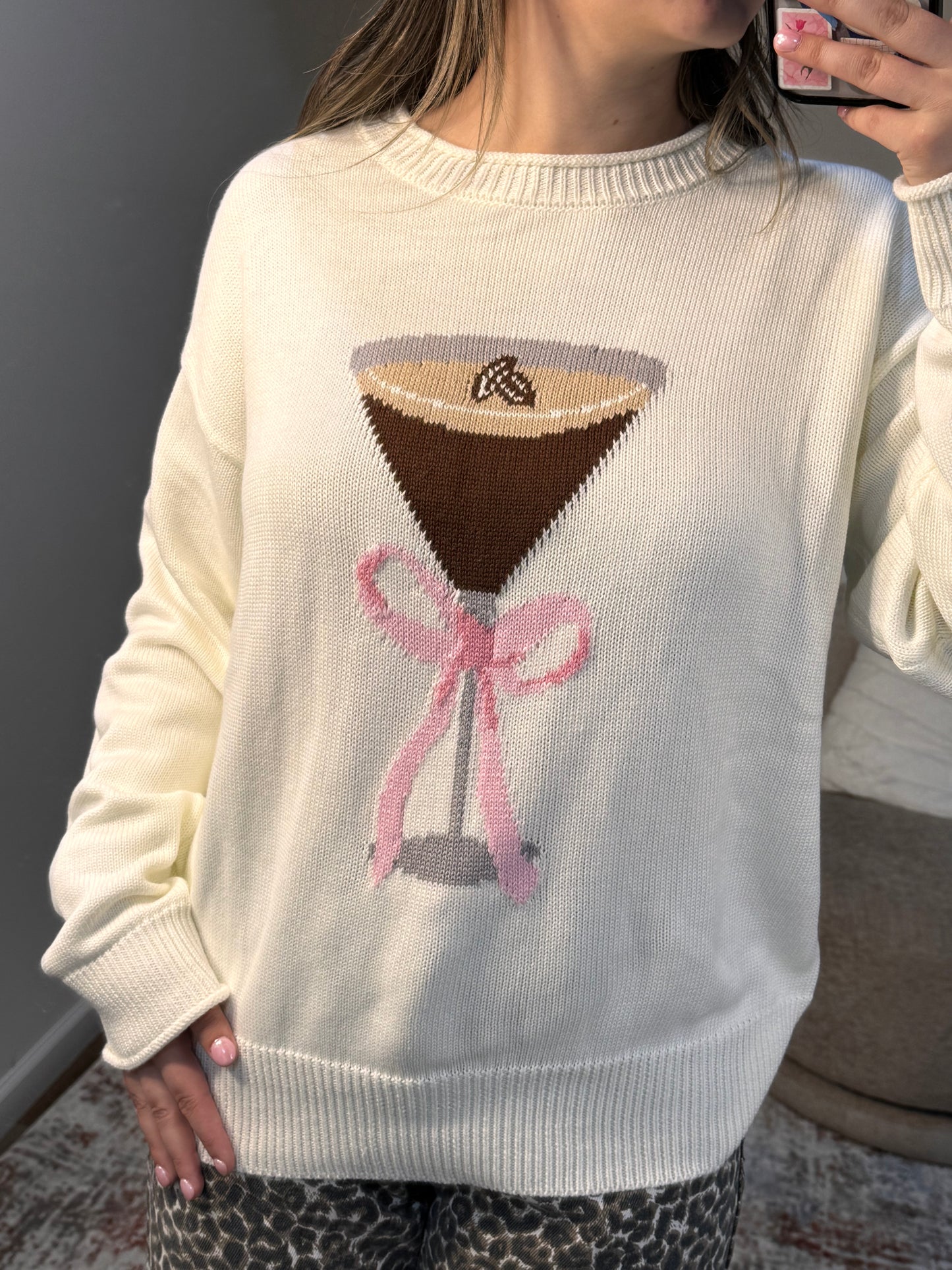Beige sweater with espresso martini and bow design worn by a person.