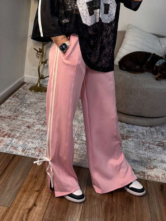 Person taking a mirror selfie wearing a black and white top with the number 28 and pink pants.