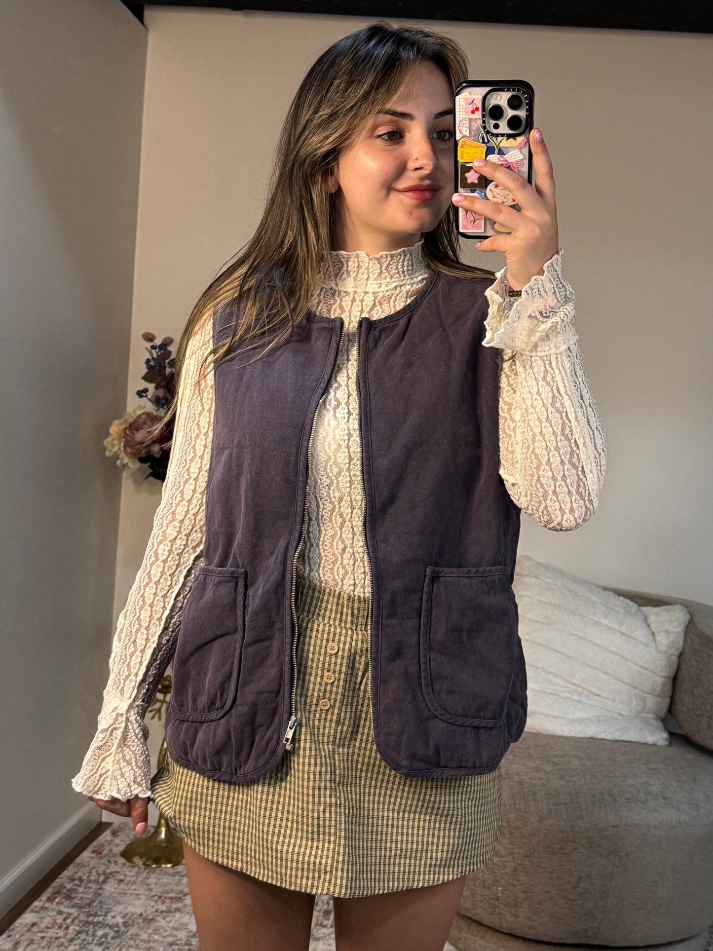 Person taking a mirror selfie wearing a layered outfit with a jacket and skirt.