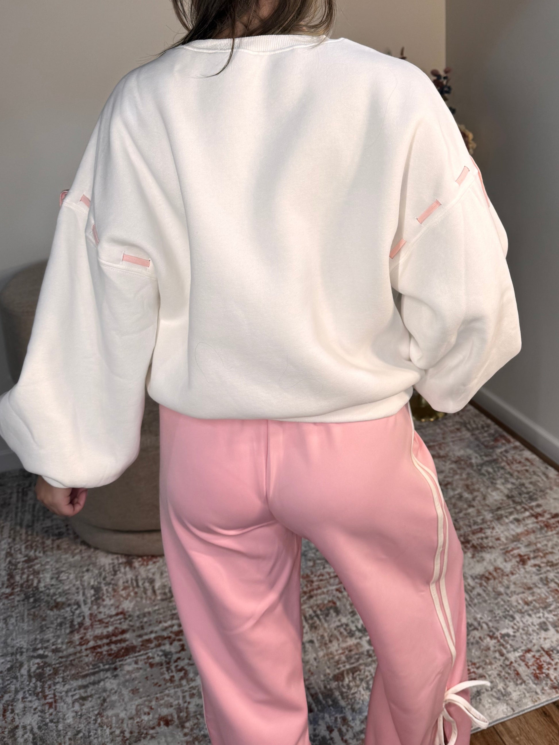 Person wearing a white hoodie and pink pants on a white floor.