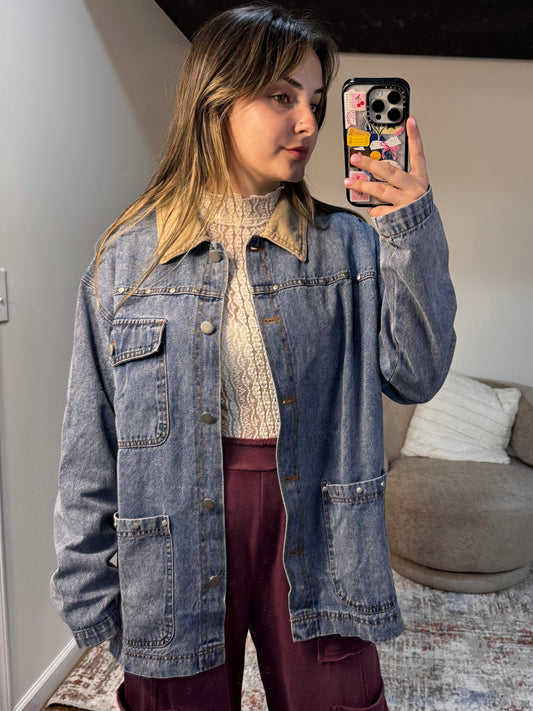 Person wearing a denim jacket in a room with a couch and rug.