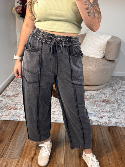 Person wearing black jeans and a beige top in a living room setting.