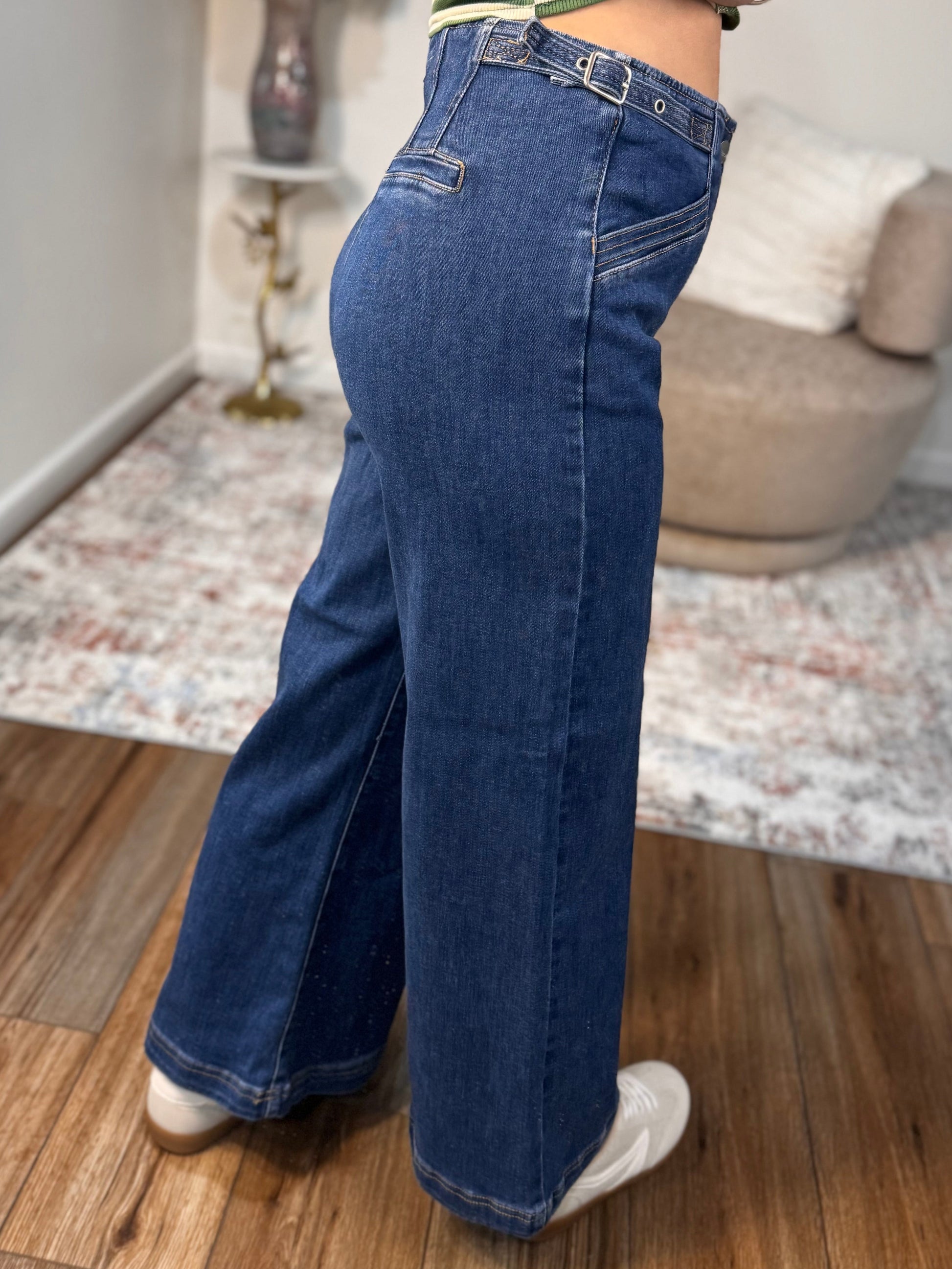 Person wearing blue jeans and a striped shirt taking a mirror selfie in a room.