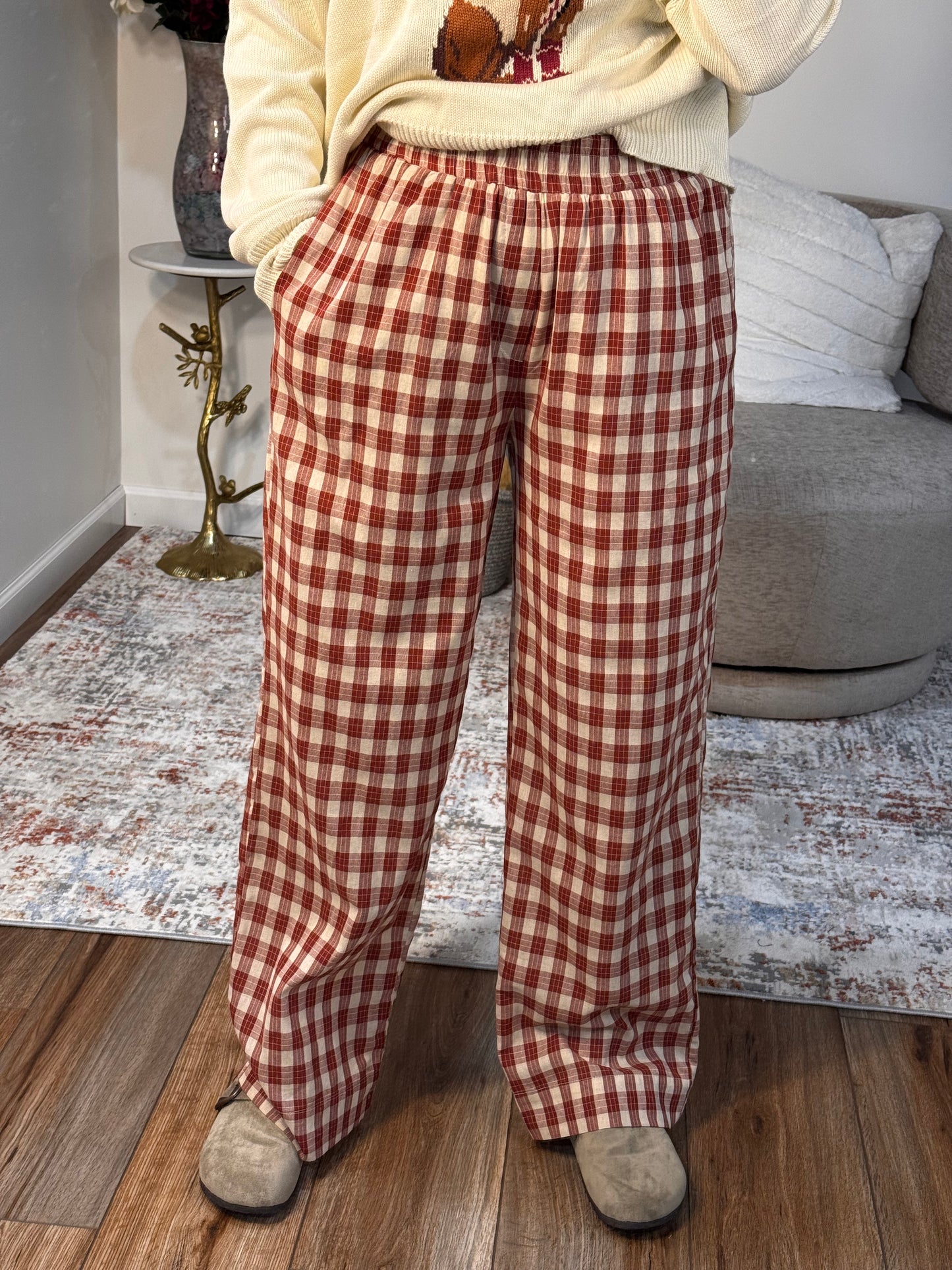Person wearing red and white checkered pants standing on a wooden floor.
