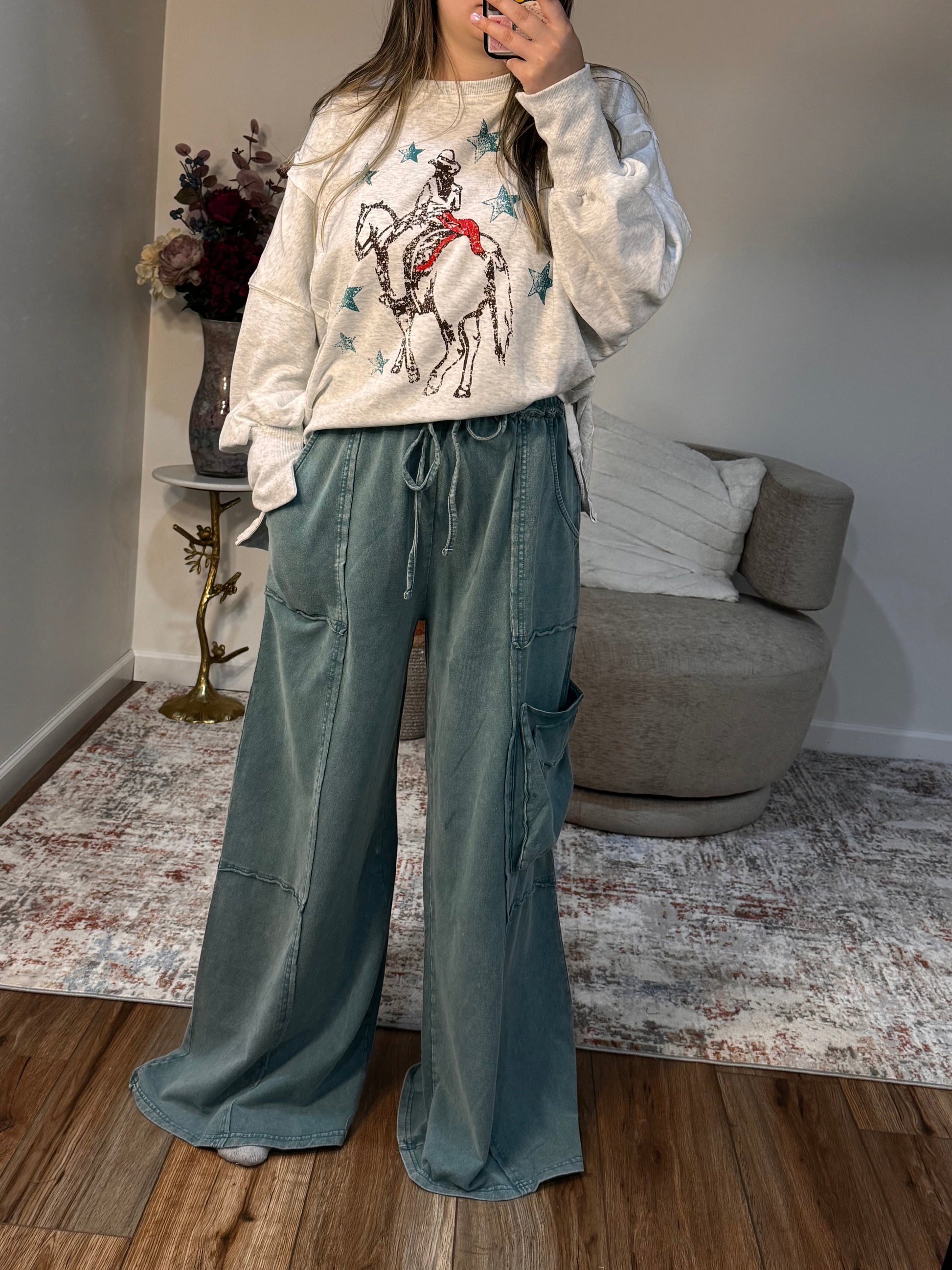 Person wearing a white jacket with colorful designs and blue jeans in a room.