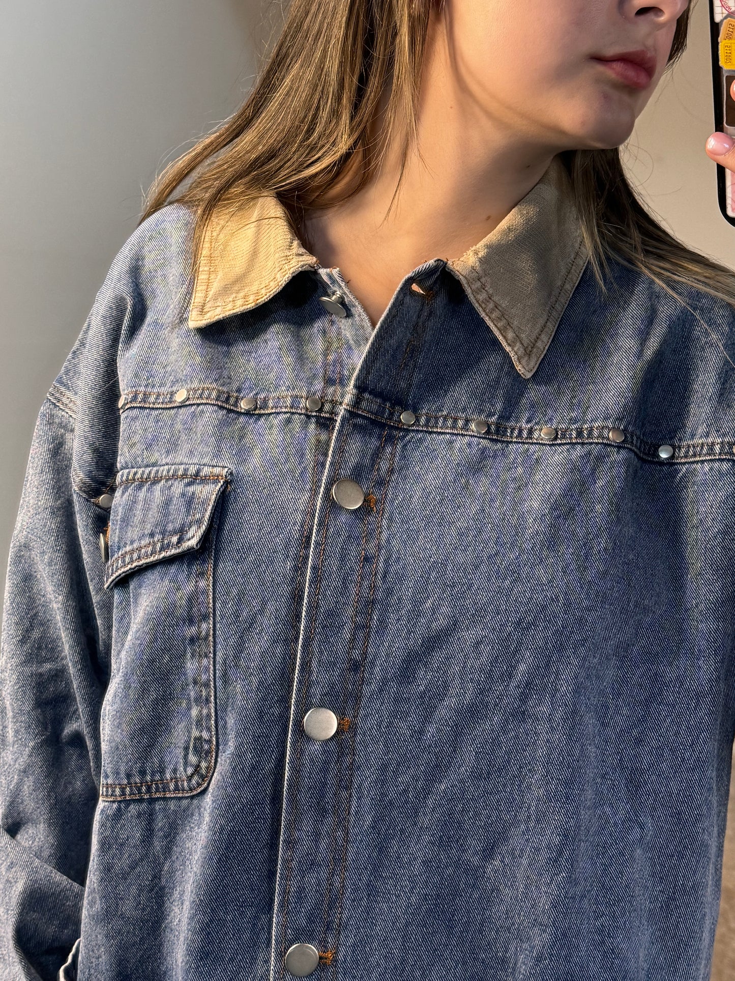 Close-up of a person wearing a blue denim shirt with a neutral background