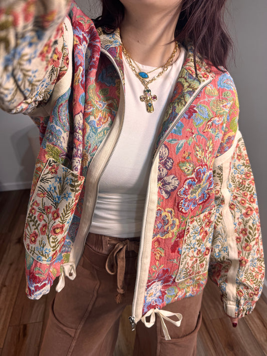 Multicolor floral and paisley quilted jacket with a front zipper and mock-neck collar.