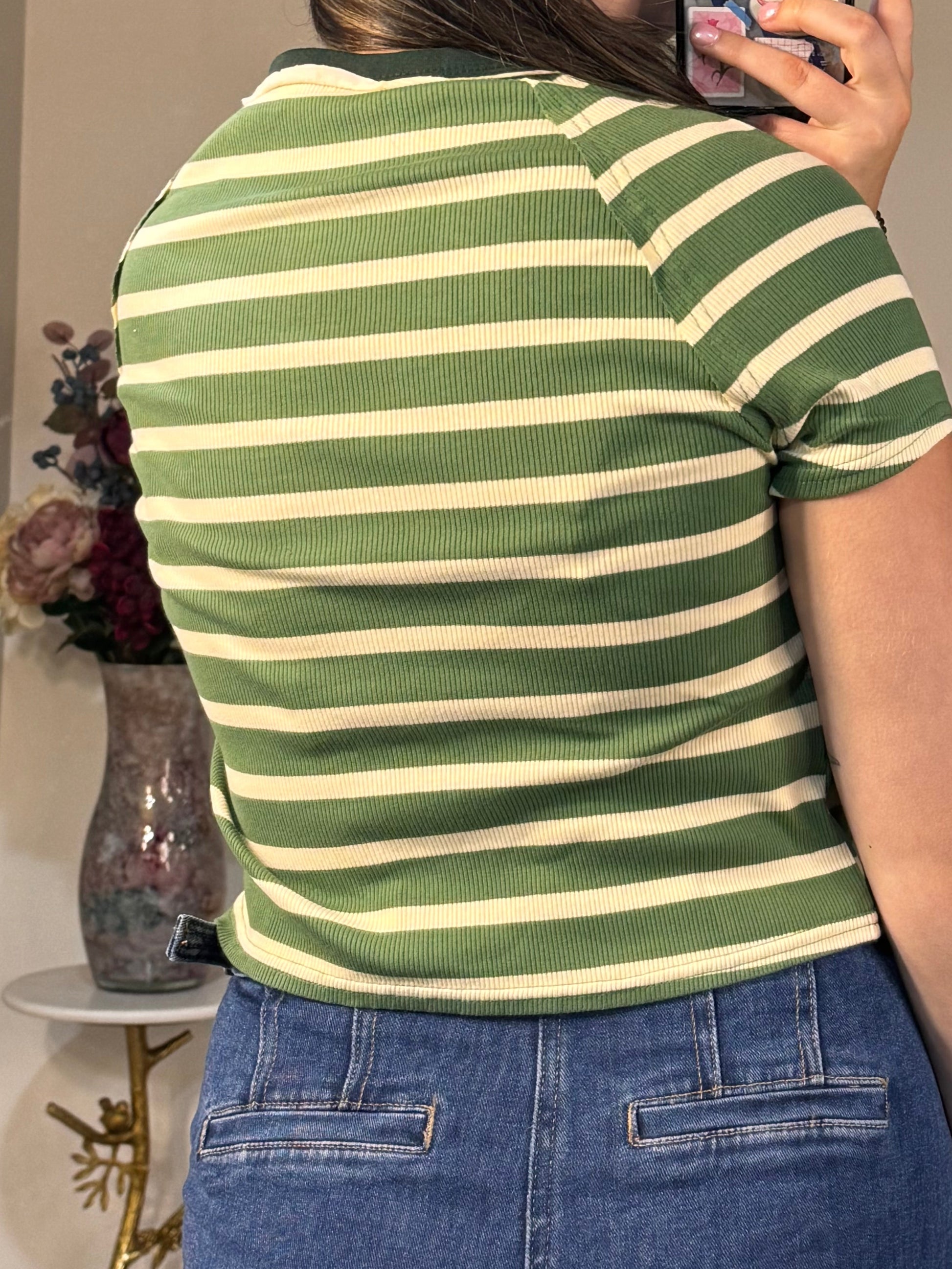 Person taking a mirror selfie wearing a green and white striped shirt and blue jeans.