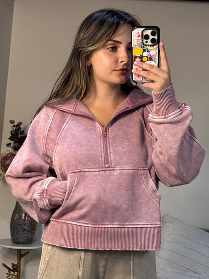 Person wearing a pink jacket taking a mirror selfie in a room.