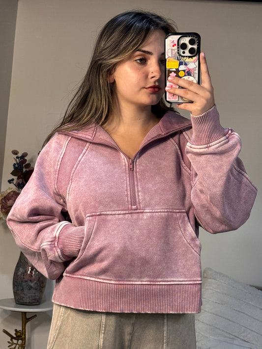 Person wearing a pink jacket taking a mirror selfie in a room.