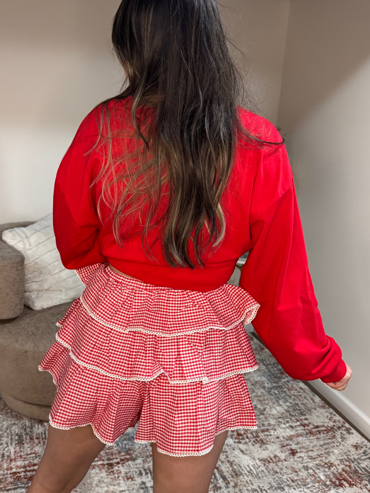 Person wearing a red top and red checkered skirt in an indoor setting