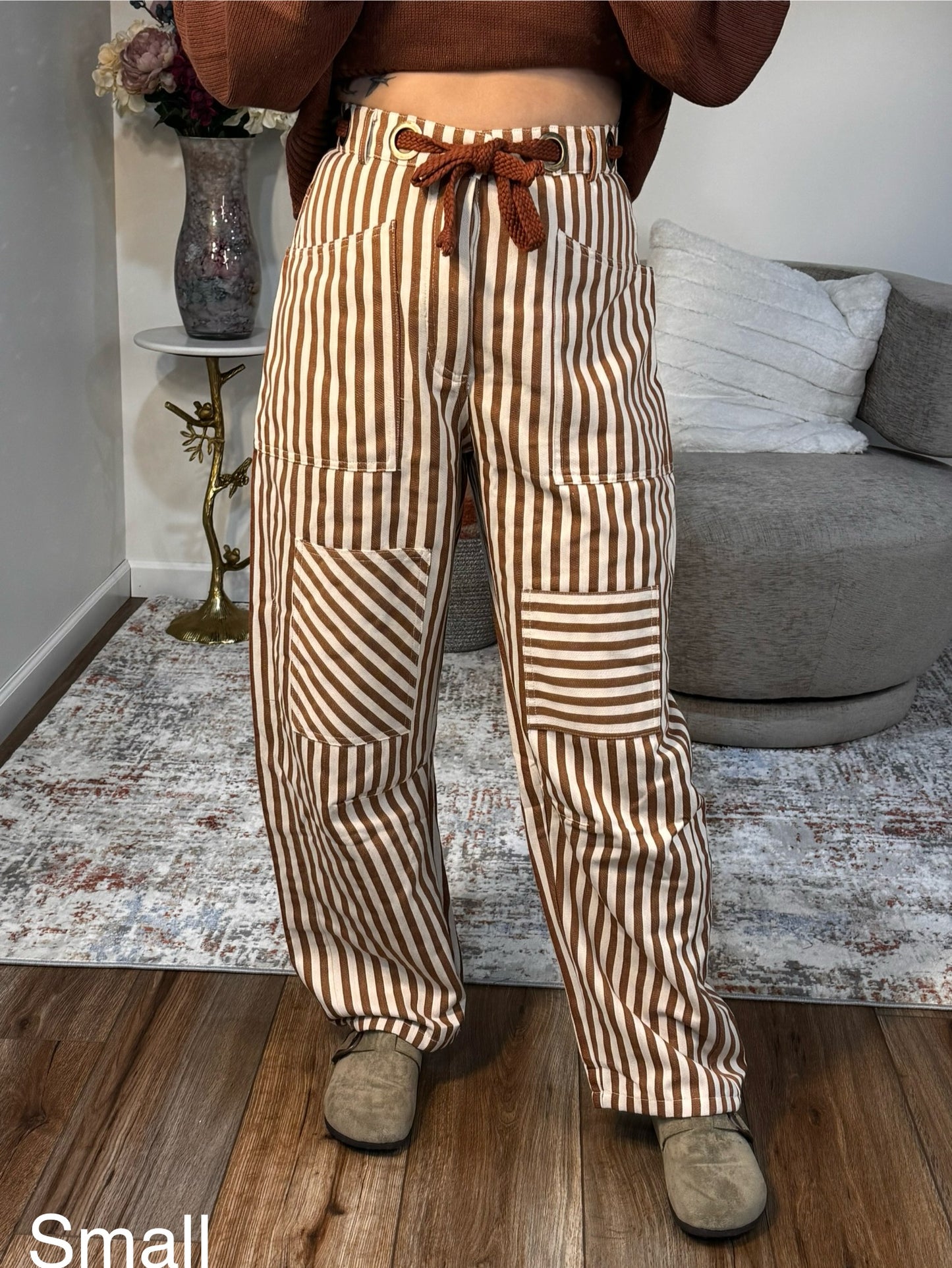 Person wearing brown and beige striped pants in a living room setting.