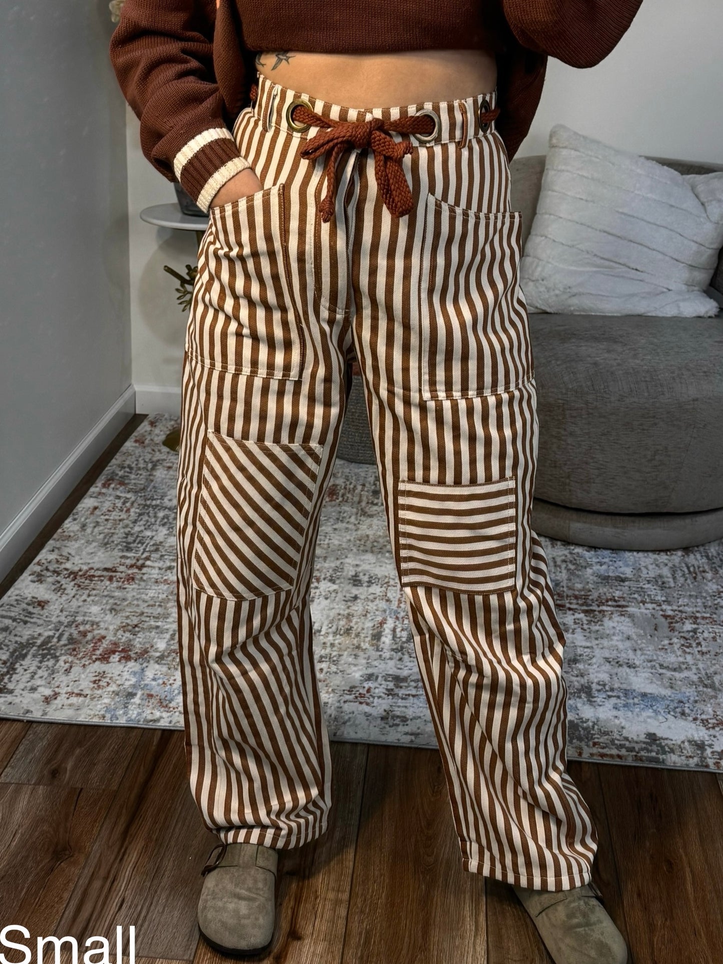 Person wearing brown and white striped pants in a living room setting.