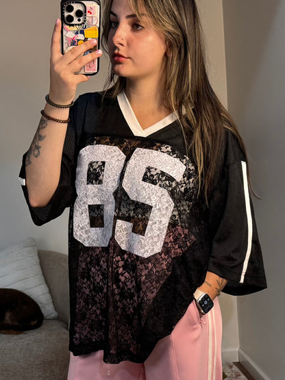Person wearing a black jersey with large white numbers, taking a mirror selfie.