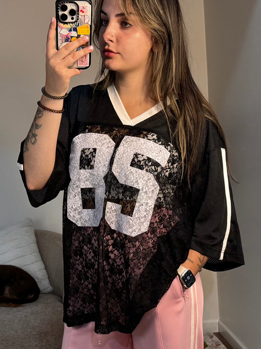 Person wearing a black jersey with large white numbers, taking a mirror selfie.