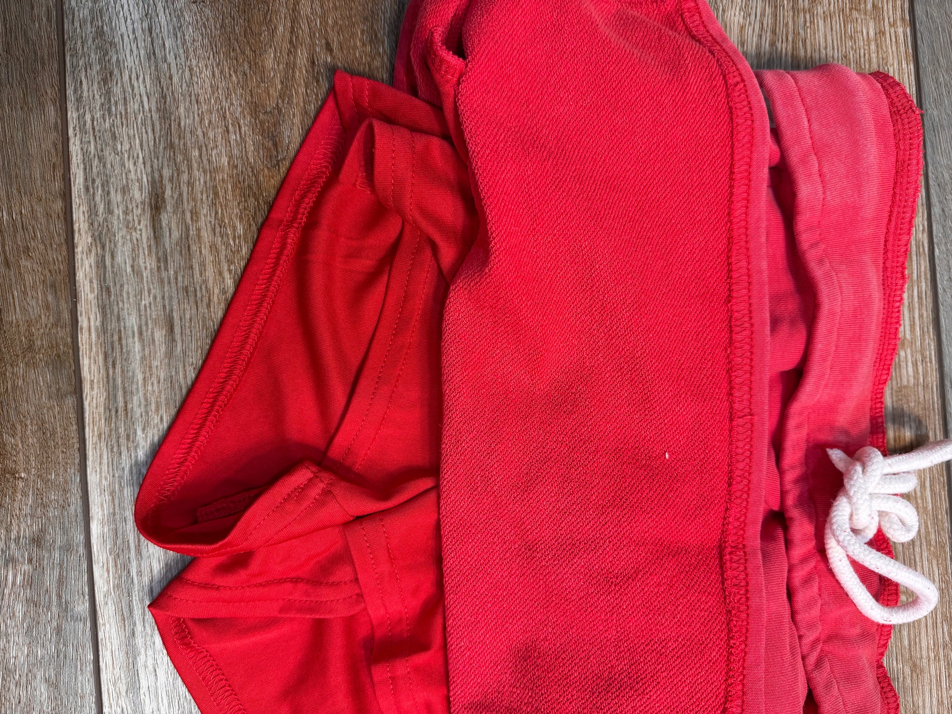 Red shorts with a white drawstring on a wooden surface
